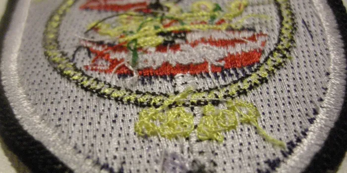 Den obehandlade baksidan på ett broderat tygmärke ämnat att sys fast.