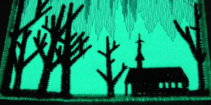 Broderat märke med fluorescerande bottenmaterial.som lyser i ett grönaktigt sken.