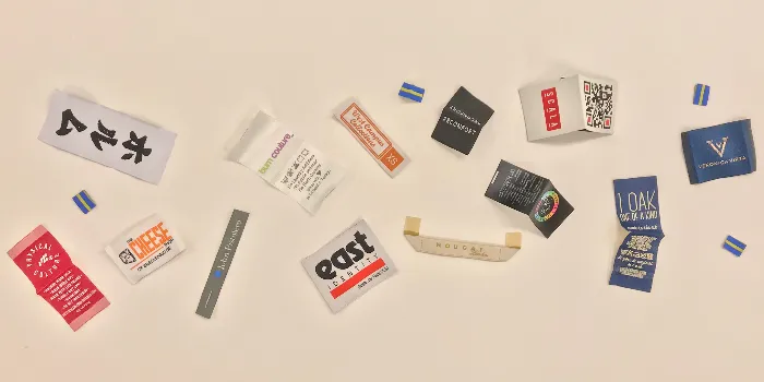 Massor av olika tryckta och vävda etiketter och labels med olika vikningar och skärningar.