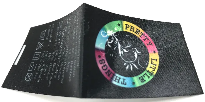 Label i 'satin' med tryckt design i många färger och färgtoningar samt tvättinstruktioner.