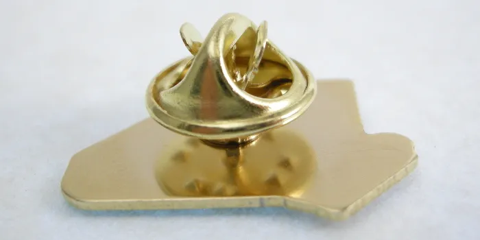 Ett fjärilslås i närbild på baksidan av en pin i metall.