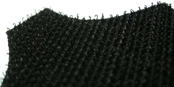 Extrem närbild på kardborren på baksidan av ett lädermärke.