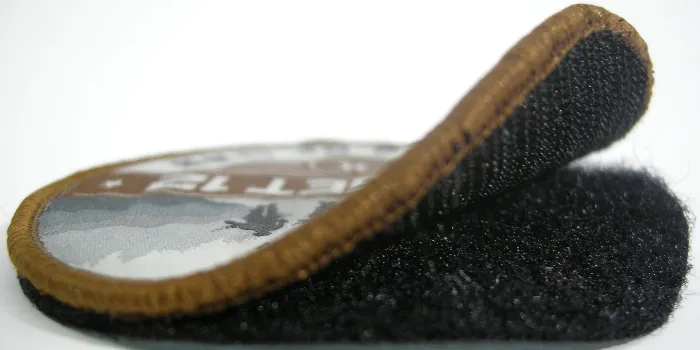 Vävd patch med kardborre på baksidan som öppnats halvvägs för att demonstrera hur den lätt kan bytas ut vid behov.